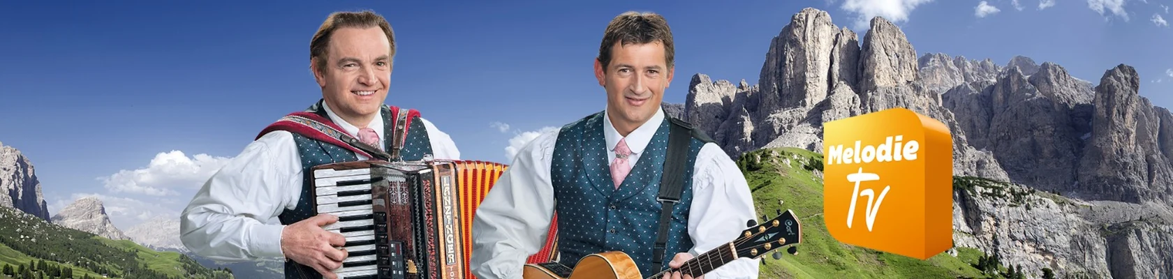 Musiker mit Akkordeon und Gitarre vor einer Berglandschaft